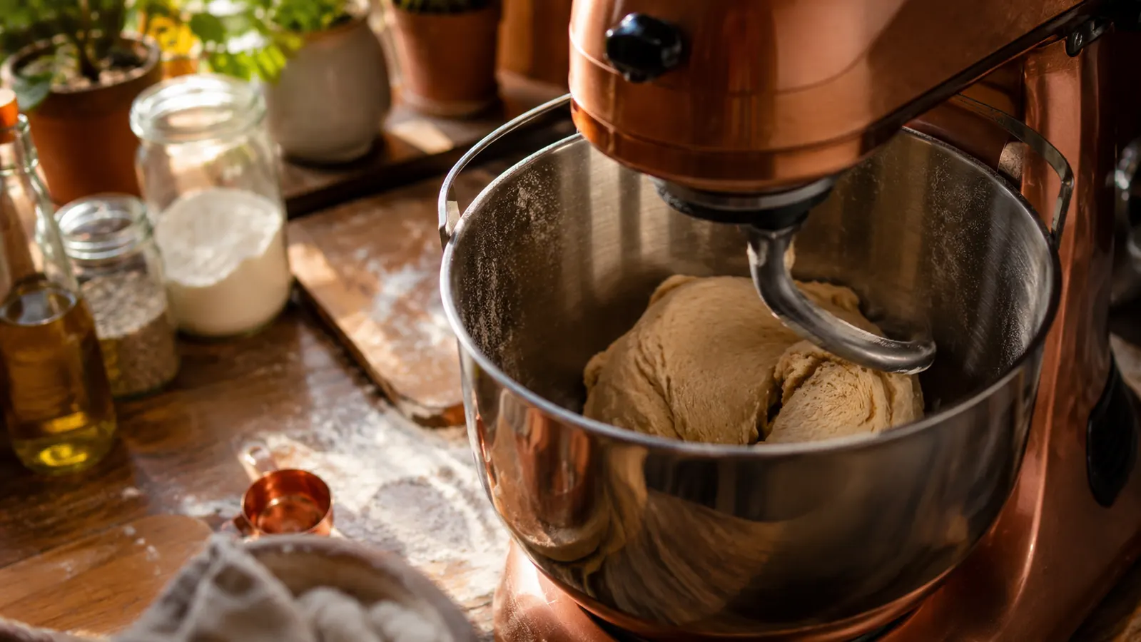 A stand mixer kneading bread dough with its dough hook attachment on a flour-dusted counter