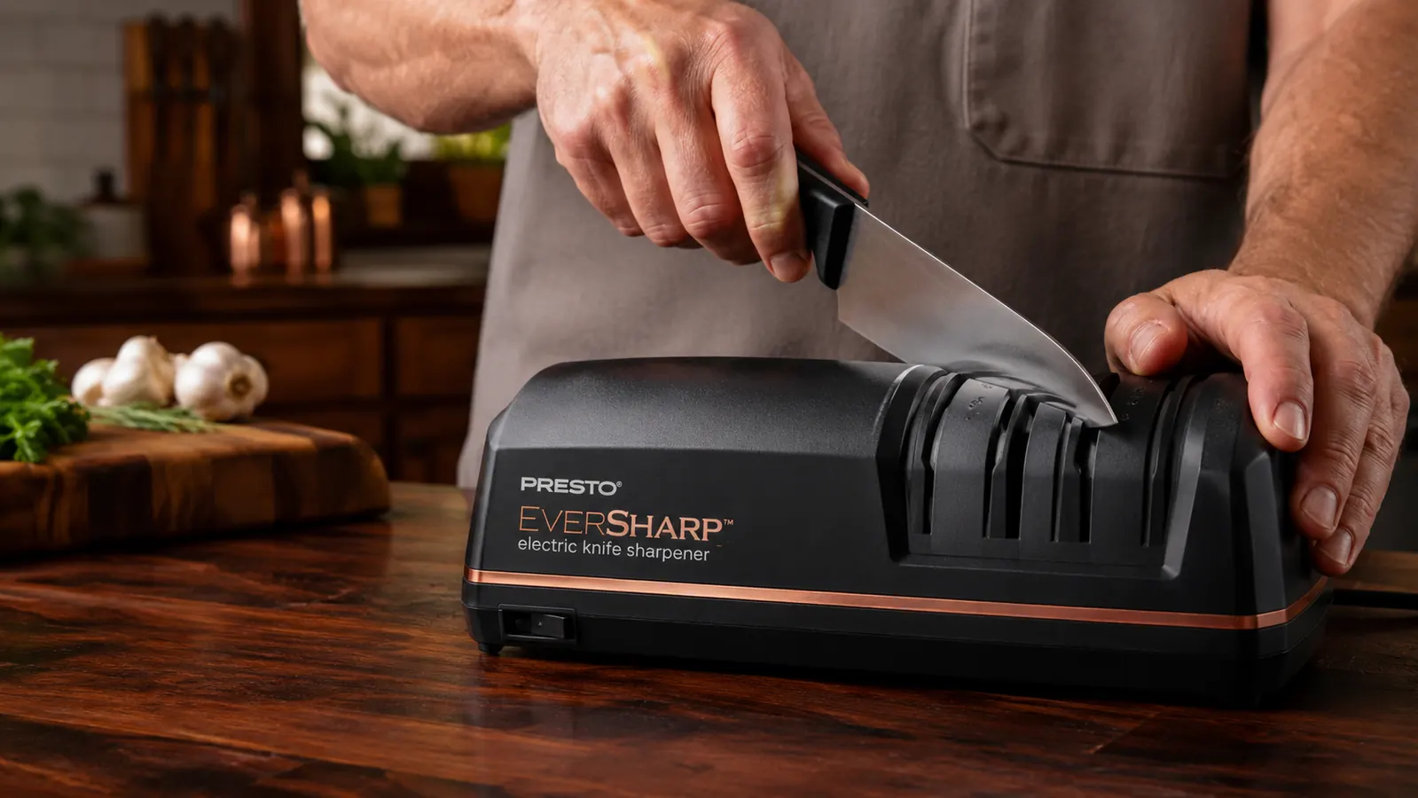 Hand pulling a chef's knife through the slots of the Presto EverSharp electric knife sharpener on a kitchen counter